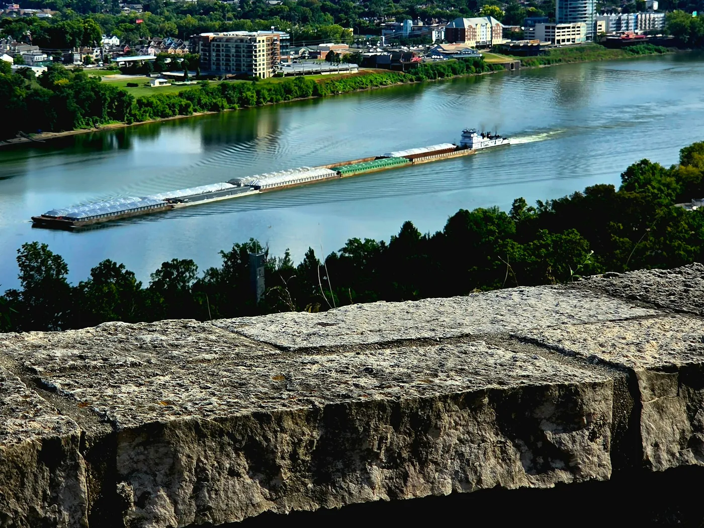 A barge on the Ohio River seen over an old stone wall